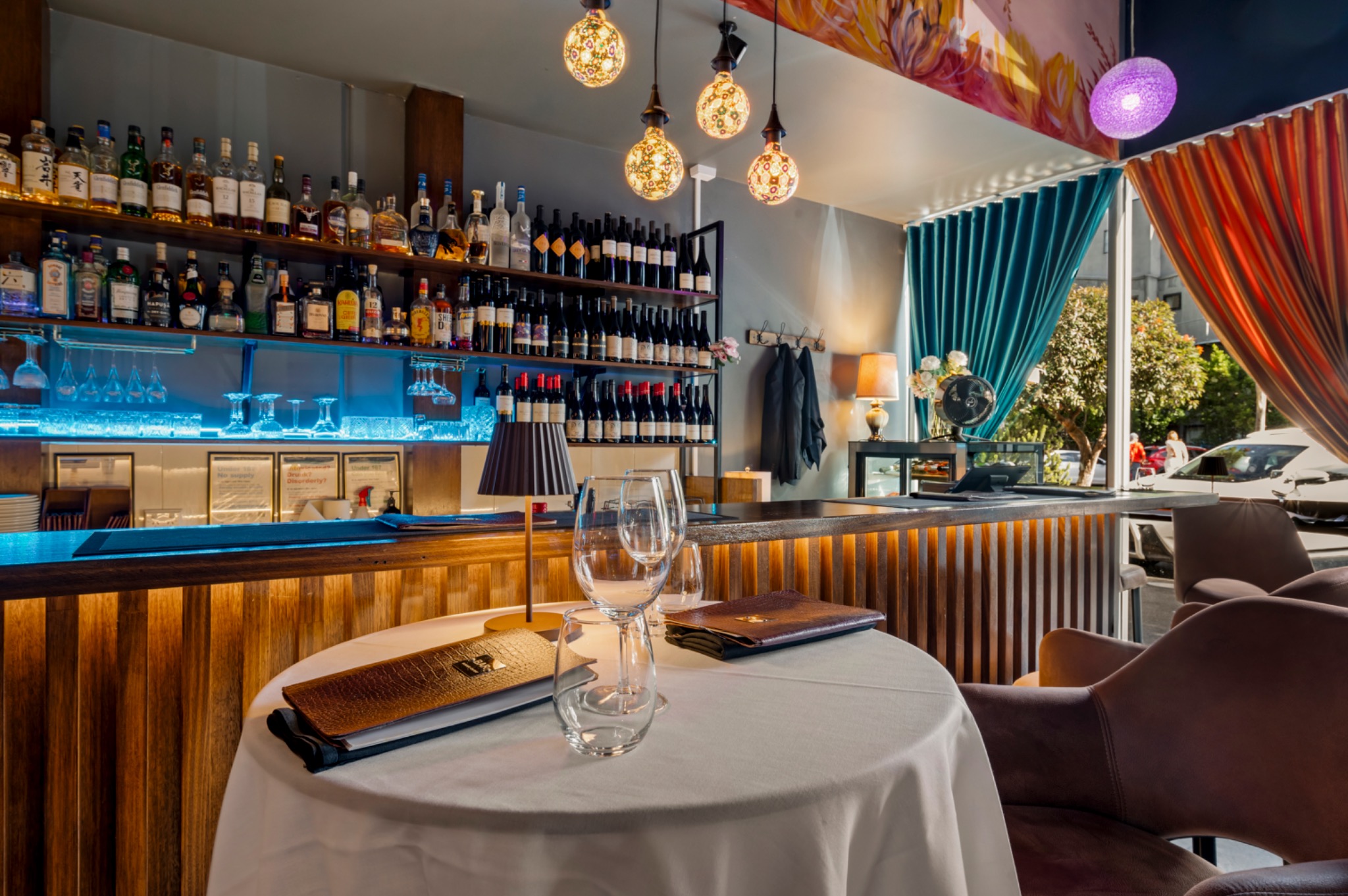Set tables by the bar, with mosaic lamps and colourful curtains