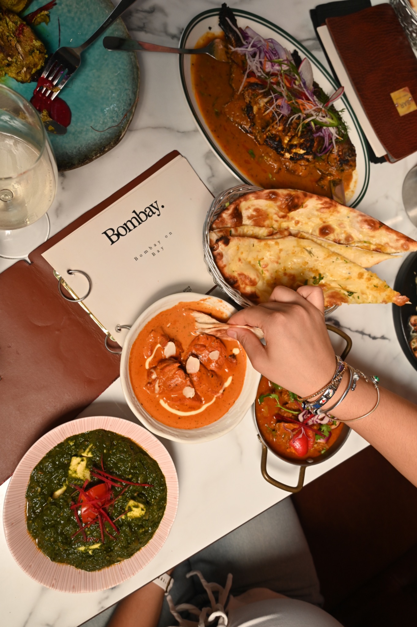 An overhead view of naan, curries and whole fish shared around the table