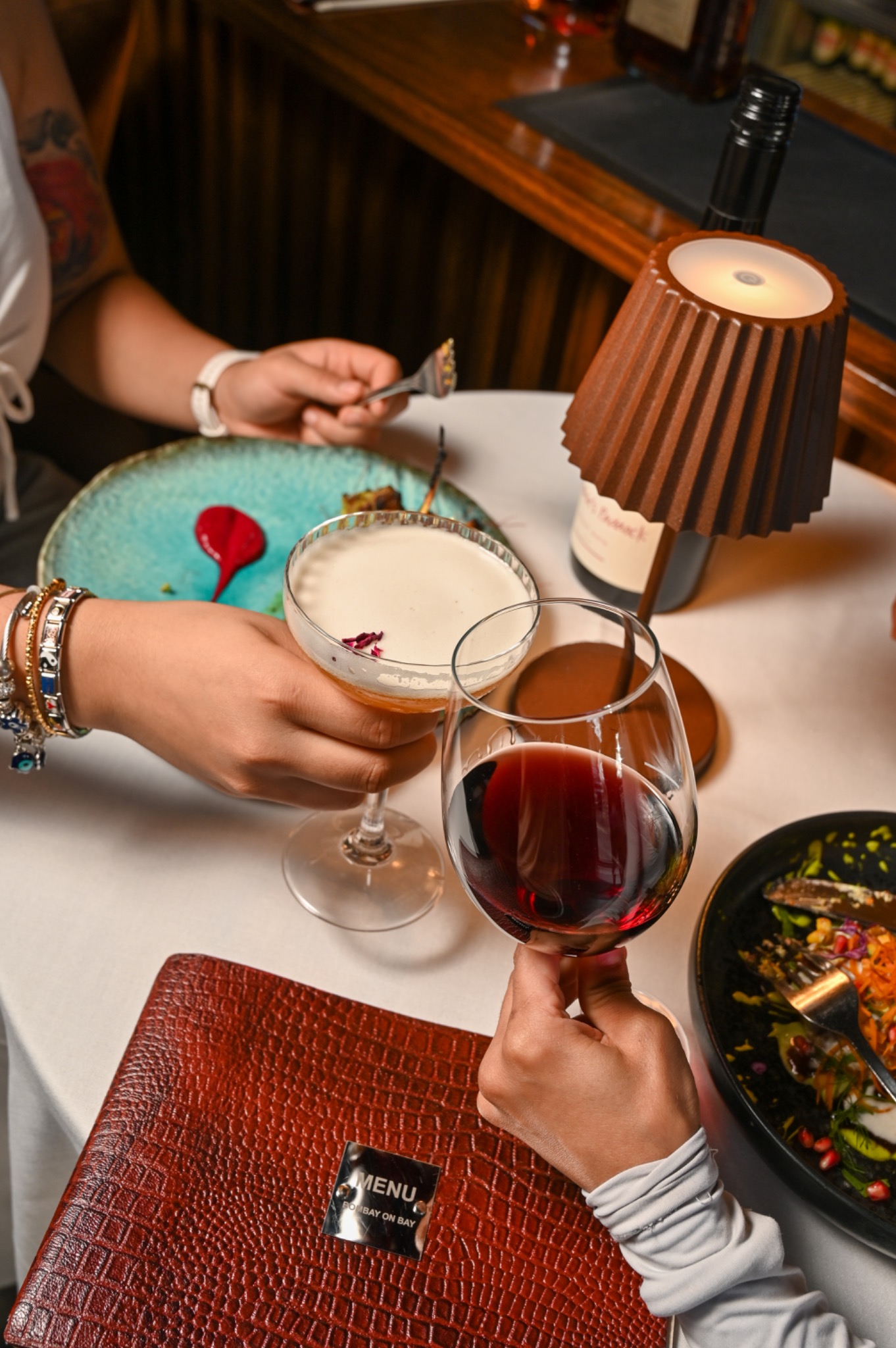 Guests raising wine glasses over a shared dinner at Bombay on Bay